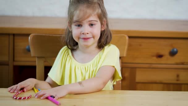 Petite fille dans une robe jaune avec des crayons dessine sur papier — Video