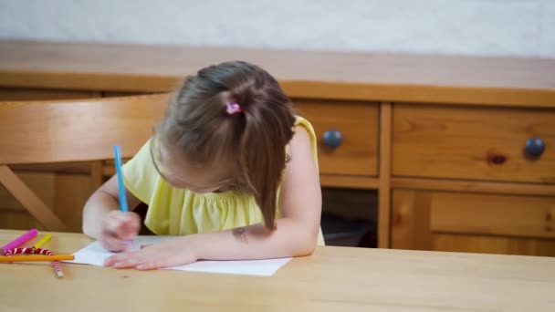 Niña en un vestido amarillo con lápices de colores dibuja sobre papel — Vídeo de stock