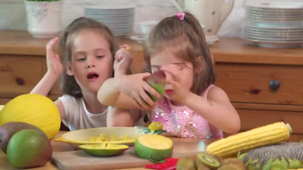 Dos chicas lindas se ríen y comen un jugoso mango amarillo — Vídeos de Stock