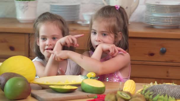 Две милые девушки смеются и едят сочный желтый манго — стоковое видео