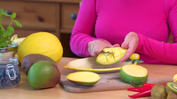 Mujer en una blusa rosa picando un jugoso mango amarillo — Vídeos de Stock