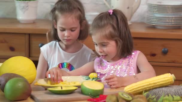 두 귀여운 여자는 웃고 육즙이 노란색 망고를 먹고있다 — 비디오