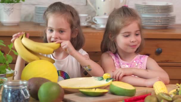 Dos chicas lindas se ríen y comen un jugoso mango amarillo — Vídeos de Stock