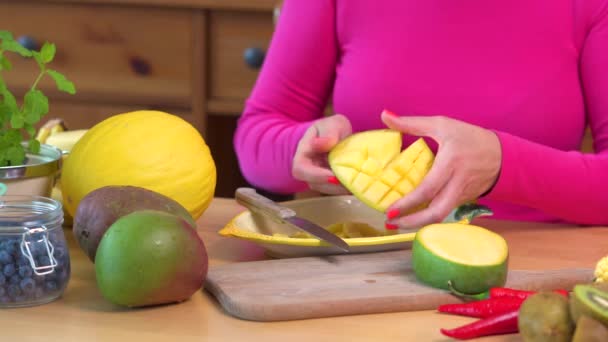 Vrouw in een roze blouse hakken een sappige gele mango — Stockvideo