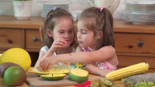 Две милые девушки смеются и едят сочный желтый манго — стоковое видео