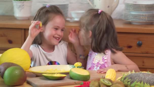 Twee schattige meiden lachen en eten een sappige gele mango — Stockvideo