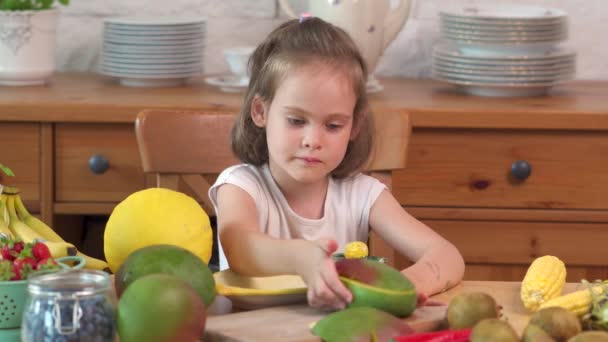 Красивая маленькая девочка ест сочную жёлтую дыню — стоковое видео