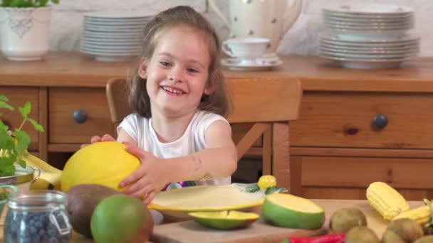 美しい小さな女の子はジューシーな黄色のメロンを食べています — ストック動画