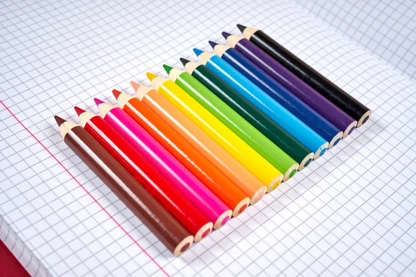 Színes ceruza ceruzák egy nyitott kockás notebook — Stock Fotó