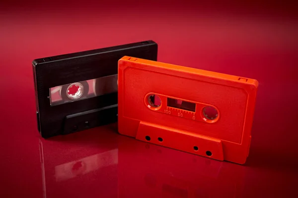 진한 빨간색 배경의 주황색 및 검은색 오디오 카세트 — 스톡 사진