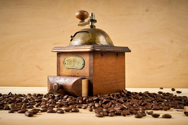 Moedor de café velho em uma mesa de madeira com sementes — Fotografia de Stock