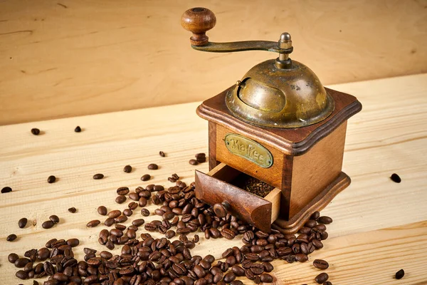 Moedor de café velho em uma mesa de madeira com sementes — Fotografia de Stock