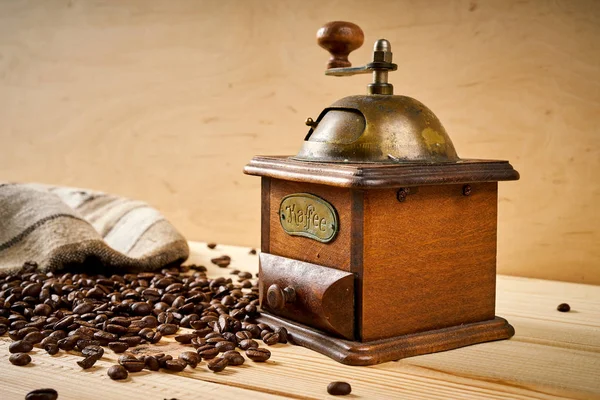 Moedor de café velho em uma mesa de madeira com sementes — Fotografia de Stock