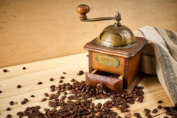 Moedor de café velho em uma mesa de madeira com sementes — Fotografia de Stock