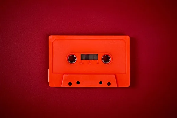 어두운 빨간색 배경에 주황색 오디오 카세트 — 스톡 사진