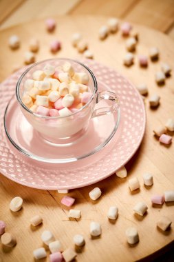 Ahşap masada sıcak süt ve renkli marshmallows ile Fincan