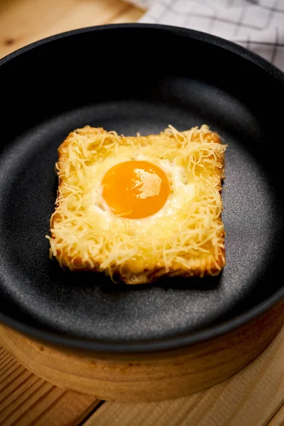 Ahşap mutfak masasında tavada kızarmış yumurta ile lezzetli tost — Stok fotoğraf
