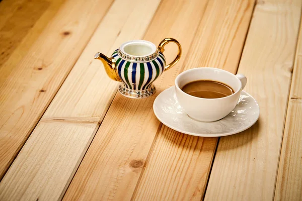 Xícara pequena com café aromático com leite na mesa de madeira — Fotografia de Stock