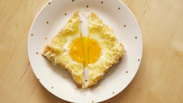 Vue du dessus du pain grillé avec oeuf frit et fromage sur une table de cuisine en bois — Video