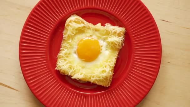 Вид сверху на тост с жареным яйцом и сыром на деревянном кухонном столе — стоковое видео