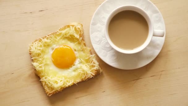 Κορυφαία θέα του τοστ με τηγανητά αυγά και καφέ σε ξύλινο τραπέζι κουζίνας — Αρχείο Βίντεο