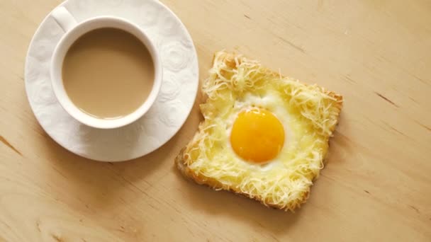Κορυφαία θέα του τοστ με τηγανητά αυγά και καφέ σε ξύλινο τραπέζι κουζίνας — Αρχείο Βίντεο