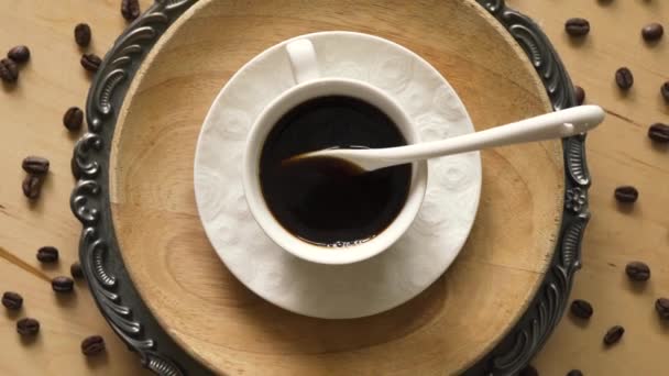Top view of coffee with spoon on decorative plate on wooden table — Stock Video