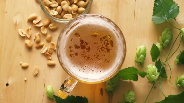 Top view of beer with foam and salty peanuts and on wooden table — Stock Video