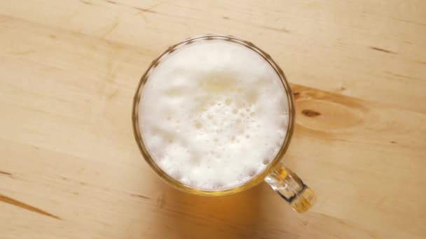 Vista superior de pinta de cerveza ligera con espuma sobre mesa de madera — Vídeos de Stock