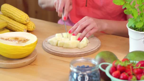 Donna in una camicetta rosa che taglia un melone giallo succoso — Video Stock
