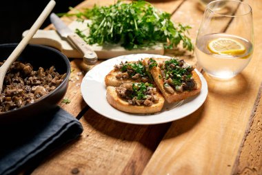 Ahşap mutfak masasında beyaz tabak üzerinde mantar ile Tost