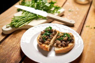 Ahşap mutfak masasında beyaz tabak üzerinde mantar ile Tost