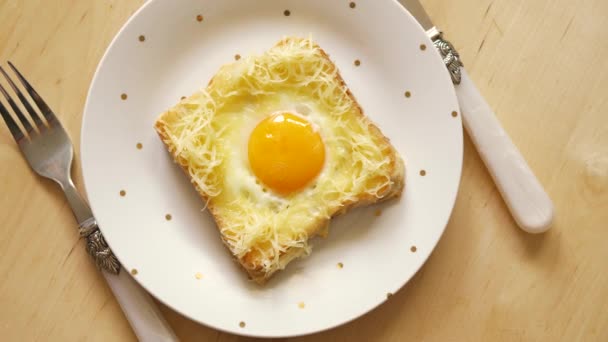 Vue du dessus du pain grillé avec oeuf frit et fromage sur une table de cuisine en bois — Video