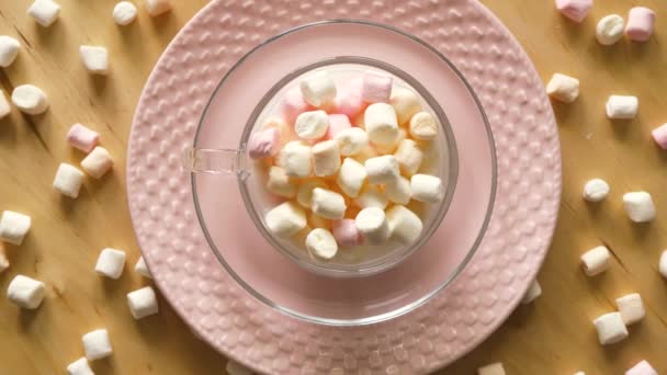 Pembe plaka ve ahşap masa üzerinde marshmallows ile fincan üst görünümü — Stok video