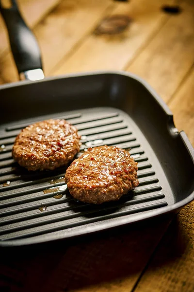 Closeup of juicy burgers fried on black grill pan — Stok fotoğraf