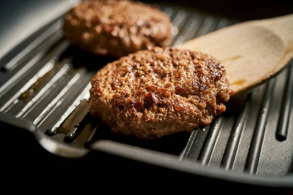 Closeup of juicy burgers fried on black grill pan — Stok fotoğraf