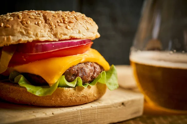 Primer plano de sabrosa hamburguesa sobre mesa de madera y fondo negro — Foto de Stock