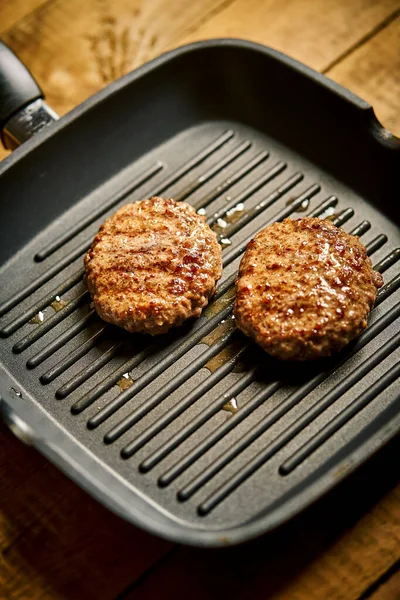 Closeup of juicy burgers fried on black grill pan — Stok fotoğraf