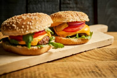 Lezzetli hamburgerleri ahşap masa ve siyah arka planda yakın plan