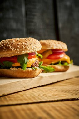 Lezzetli hamburgerleri ahşap masa ve siyah arka planda yakın plan