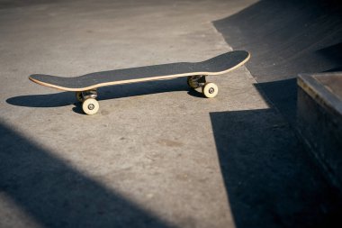 Sıcak bir günde beton kaykay parkındaki siyah kaykayın görüntüsü