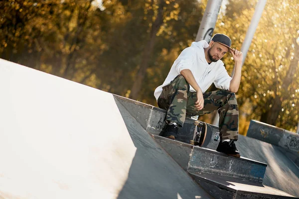 Hombre en skatepark con monopatín en cálido día de otoño — Foto de Stock