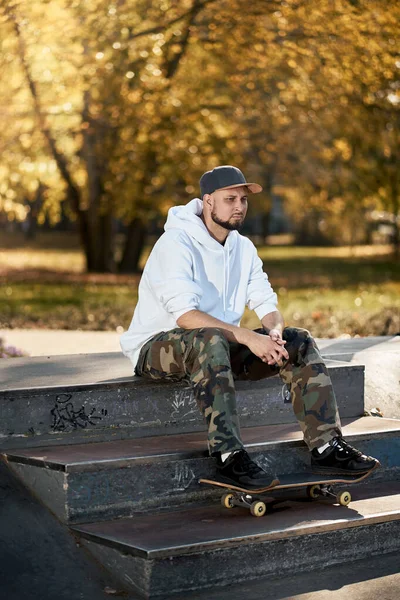 Hombre en skatepark con monopatín en cálido día de otoño —  Fotos de Stock