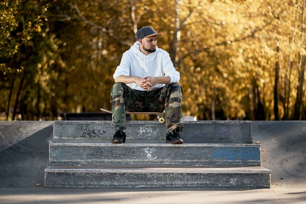 Hombre en skatepark con monopatín en cálido día de otoño —  Fotos de Stock