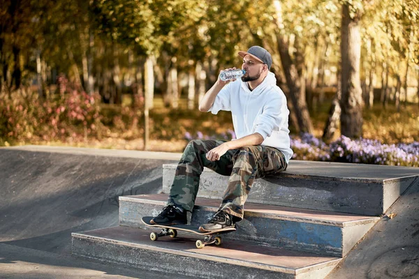 Hombre en skatepark con monopatín en cálido día de otoño —  Fotos de Stock