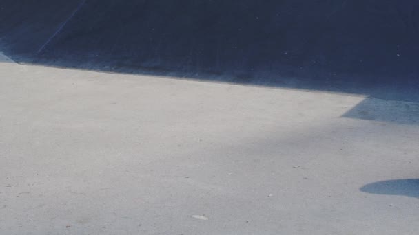 Чорний скейтборд їде в бетонному скейтпарку в сонячний день — стокове відео