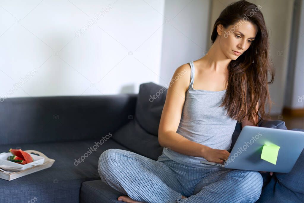 woman in pajamas working remotely at home during a pandemic