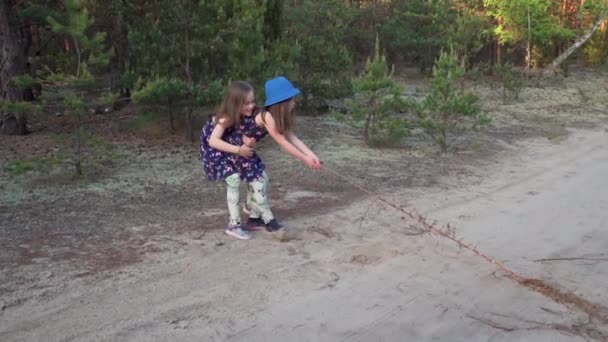 Niñas en vestidos tirar de la raíz en el camino del bosque — Vídeo de stock