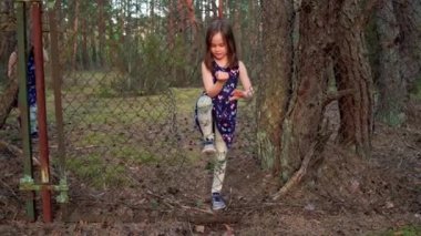 Elbiseli kızlar yaz ormanlarında çitin içinden geçiyorlar.