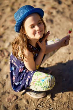 Bahar çam ormanında poz veren mavi şapkalı küçük kız.